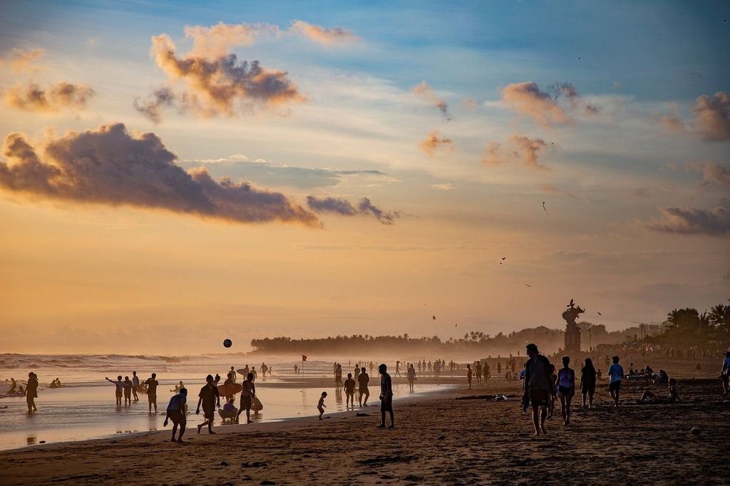 Ein malerischer Sonnenuntergang am Strand von Bali mit Silhouetten von Menschen, die den Moment genießen.