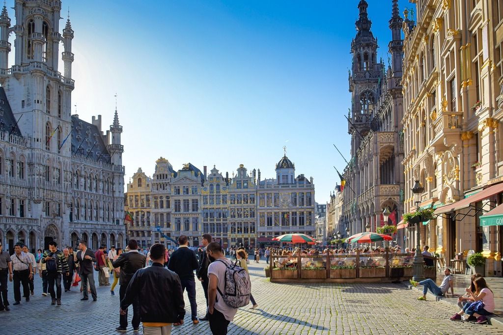 Die Grand Place in Brüssel, Belgien, voller Menschen mit sonnigem Wetter und historischen Gebäuden.
