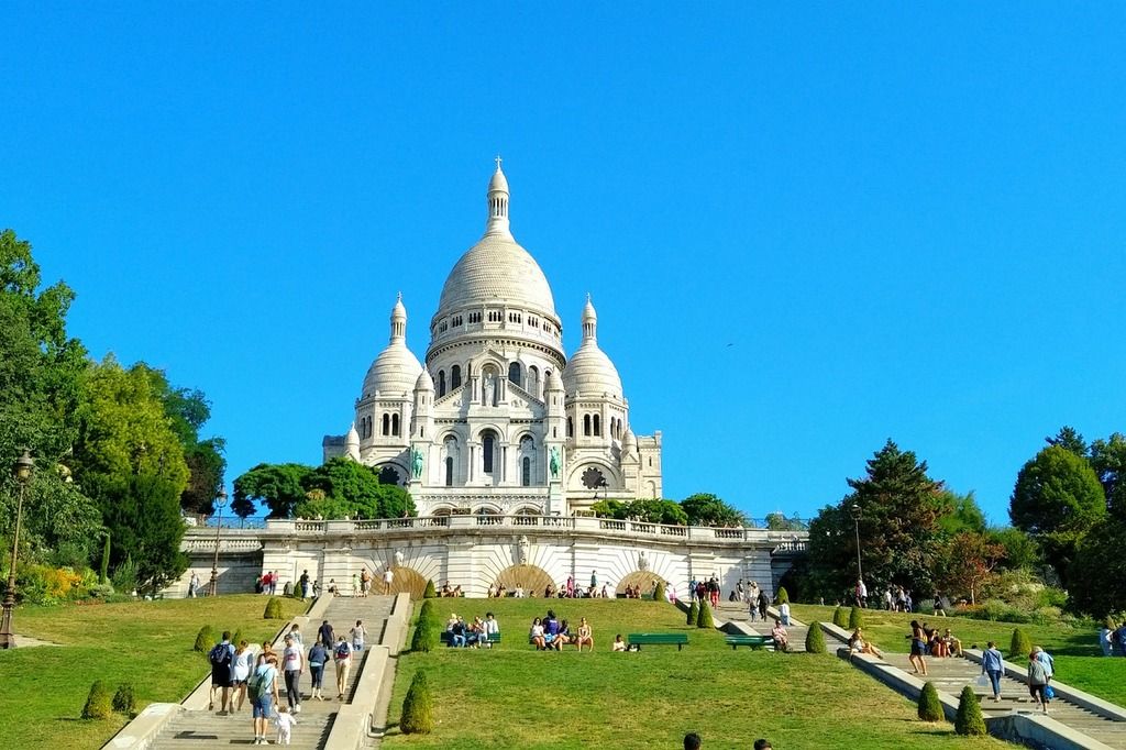 Die Basilika Sacré-Cœur in Montmartre, Paris, mit grünen Gärten im Vordergrund.