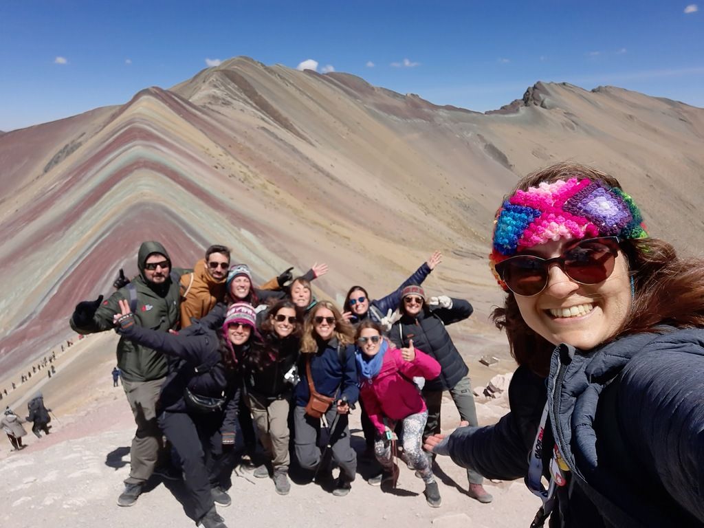 WeRoad-Gruppe von Reisenden macht Selfie vor dem bunten Regenbogenberg Vinicunca in Peru.