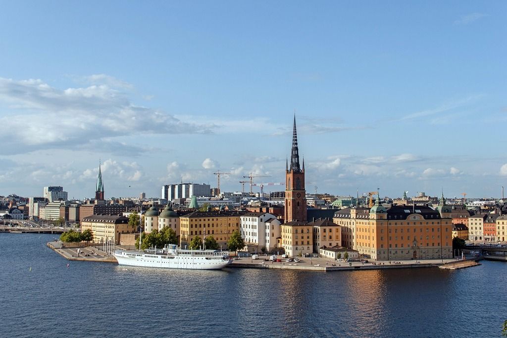 Blick auf die Insel Riddarholmen in Stockholm mit historischen Gebäuden und einem weißen Schiff am Ufer.
