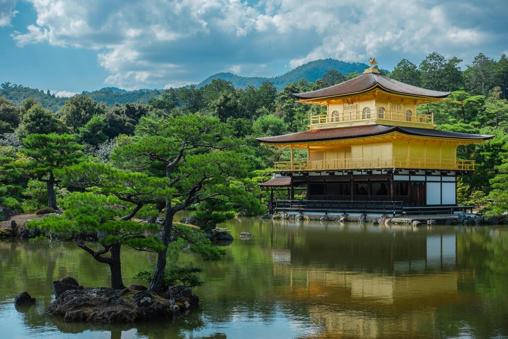 Goldener Pavillon (Kinkaku-ji) in Kyoto, umgeben von einem ruhigen See und grünen Bäumen.