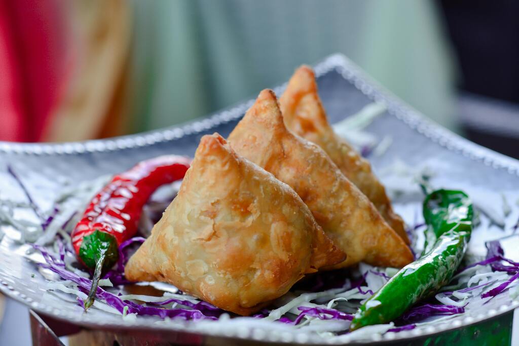 Knusprige goldene Samosas, gefüllt mit herzhaften Gewürzen, serviert mit scharfen Chilis – ein beliebtes Streetfood in der indischen Küche.