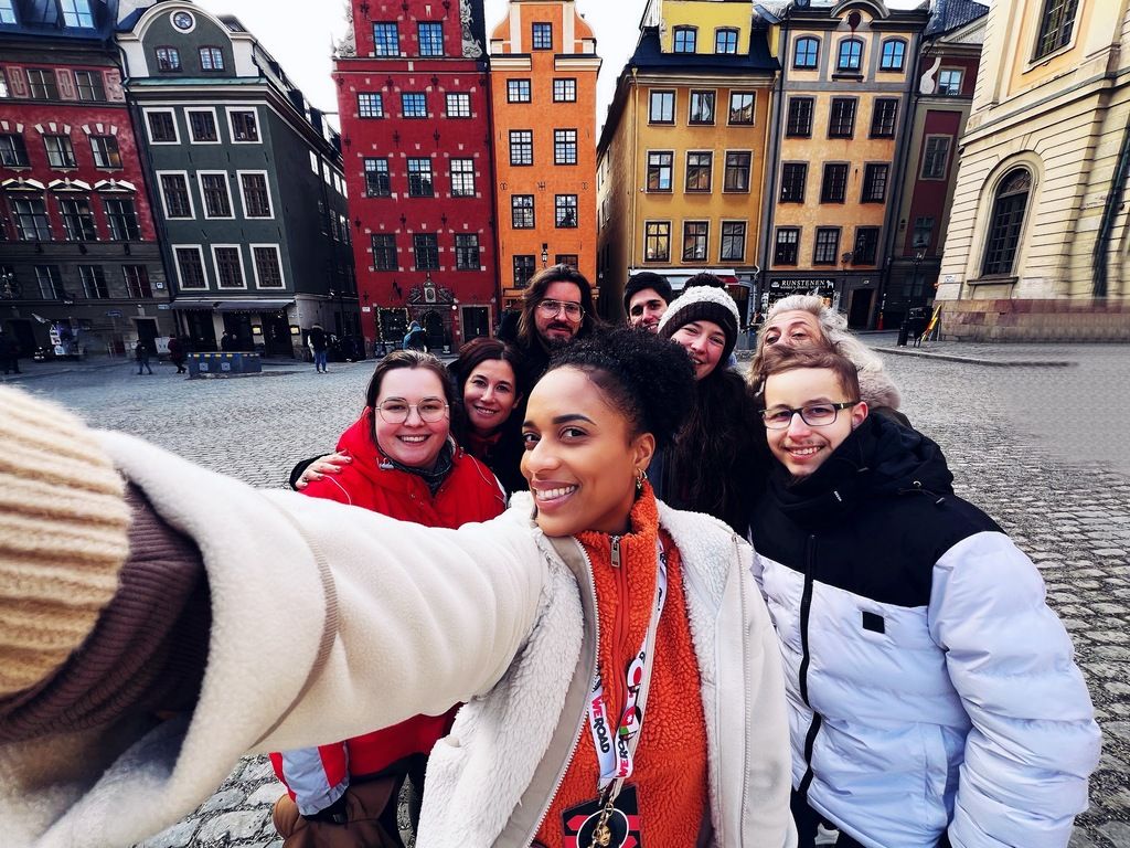 Gruppenfoto einer WeRoad-Reisegruppe in Stockholm vor den berühmten bunten Häusern der Altstadt.