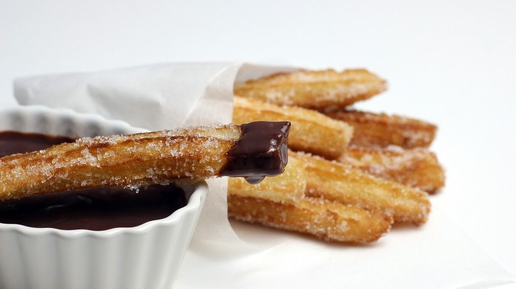 Spanische Churros mit Zucker bestreut und in heiße Schokolade getaucht.