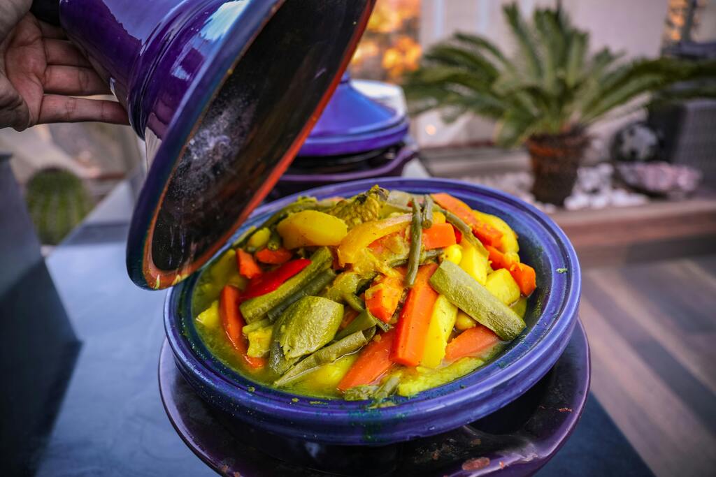 Traditionelles marokkanisches Tajine-Gericht mit Gemüse in einer violetten Keramikschale.