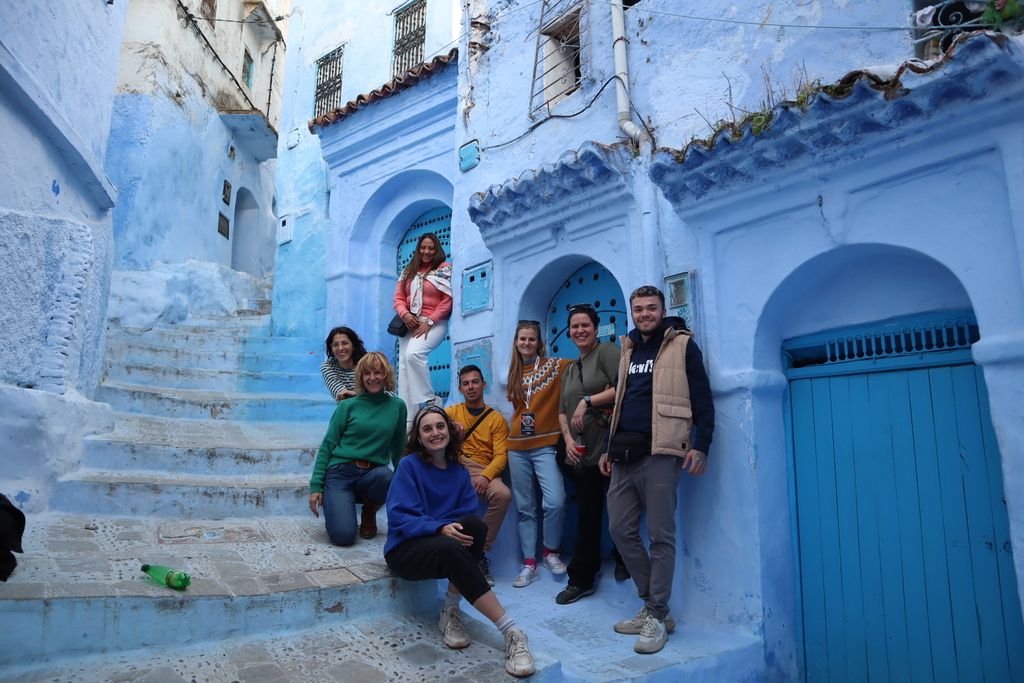 Eine Gruppe von Reisenden in den blauen Gassen von Chefchaouen während einer WeRoad-Gruppenreise in Marokko.