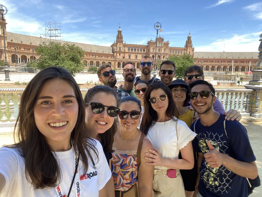 WeRoad-Gruppenreise in Spanien: Eine fröhliche Gruppe von Reisenden macht ein Selfie auf der Plaza de España in Sevilla.