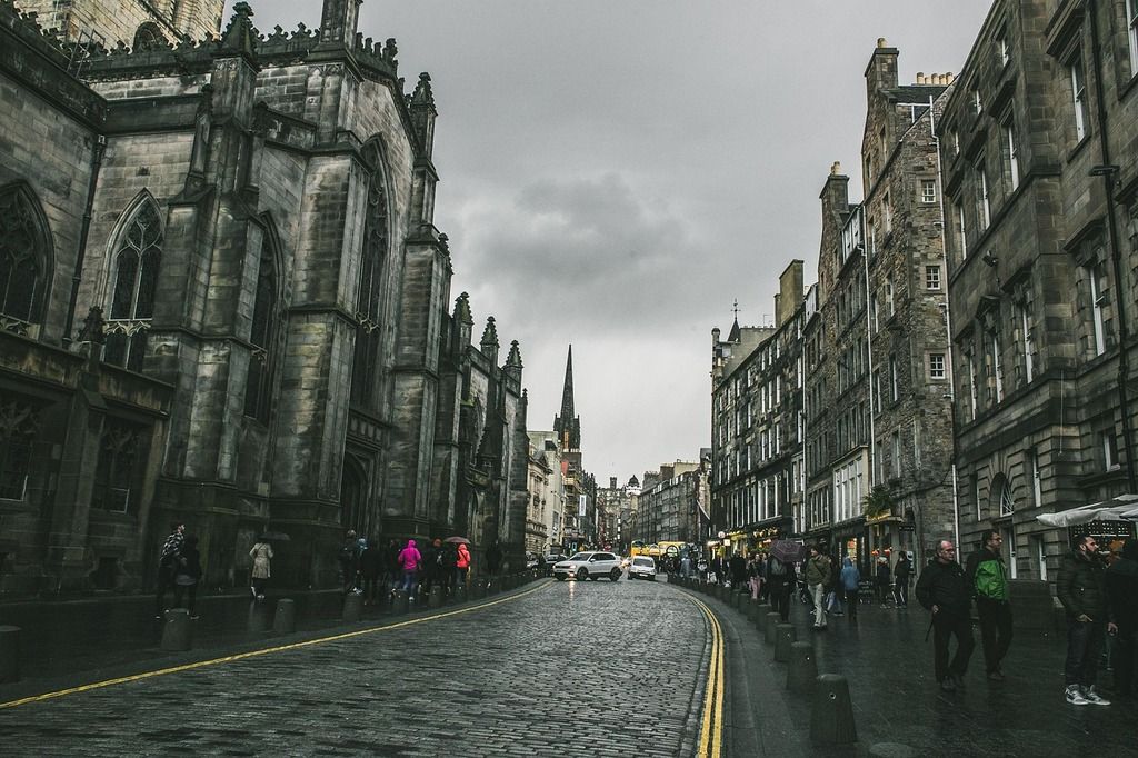 Die Royal Mile in Edinburgh, eine historische Straße voller Menschen und Geschäfte an einem regnerischen Tag.