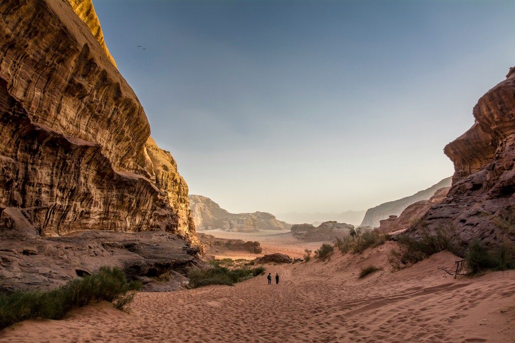 Wanderer im Wadi Rum, Jordanien, zwischen imposanten Felsformationen bei Sonnenuntergang