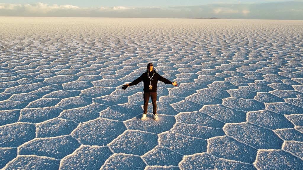 Person steht mitten im weißen Salzsee Salar de Uyuni in Bolivien