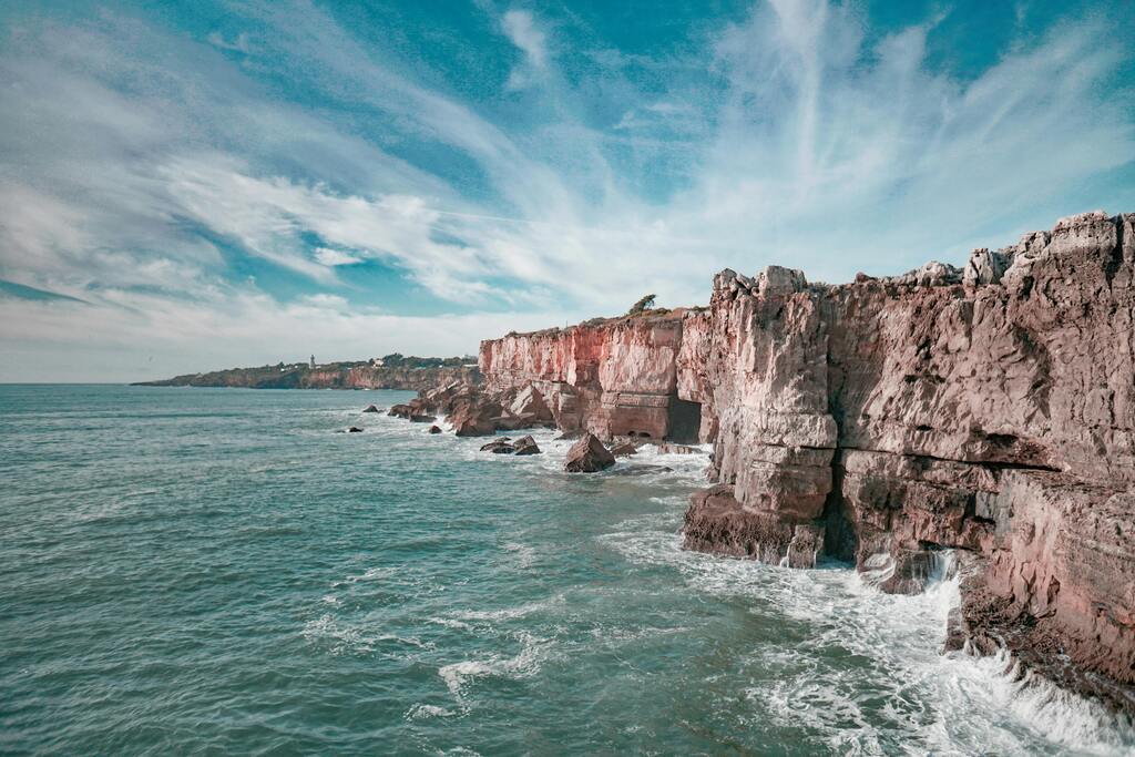 Steile Klippen an der Atlantikküste mit türkisfarbenem Wasser und dramatischem Himmel in Portugal.