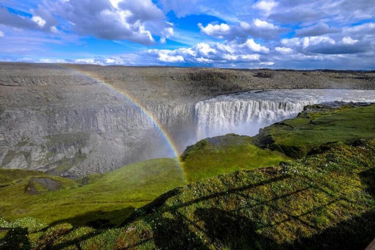 Mächtiger Dettifoss Wasserfall mit Regenbogen über der Schlucht.