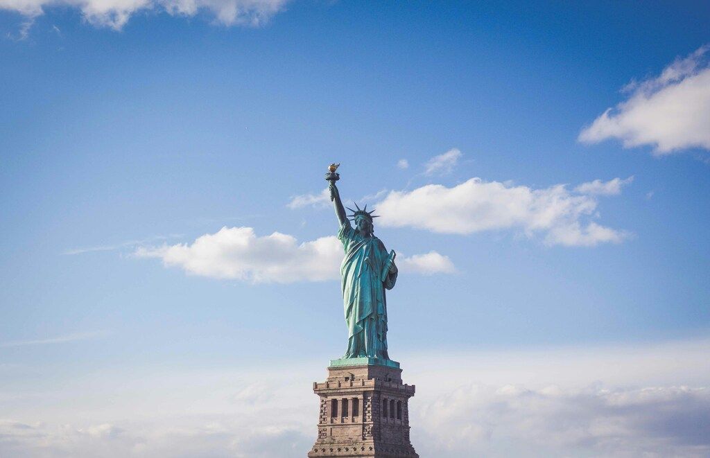 Die Freiheitsstatue vor einem blauen Himmel mit Wolken.