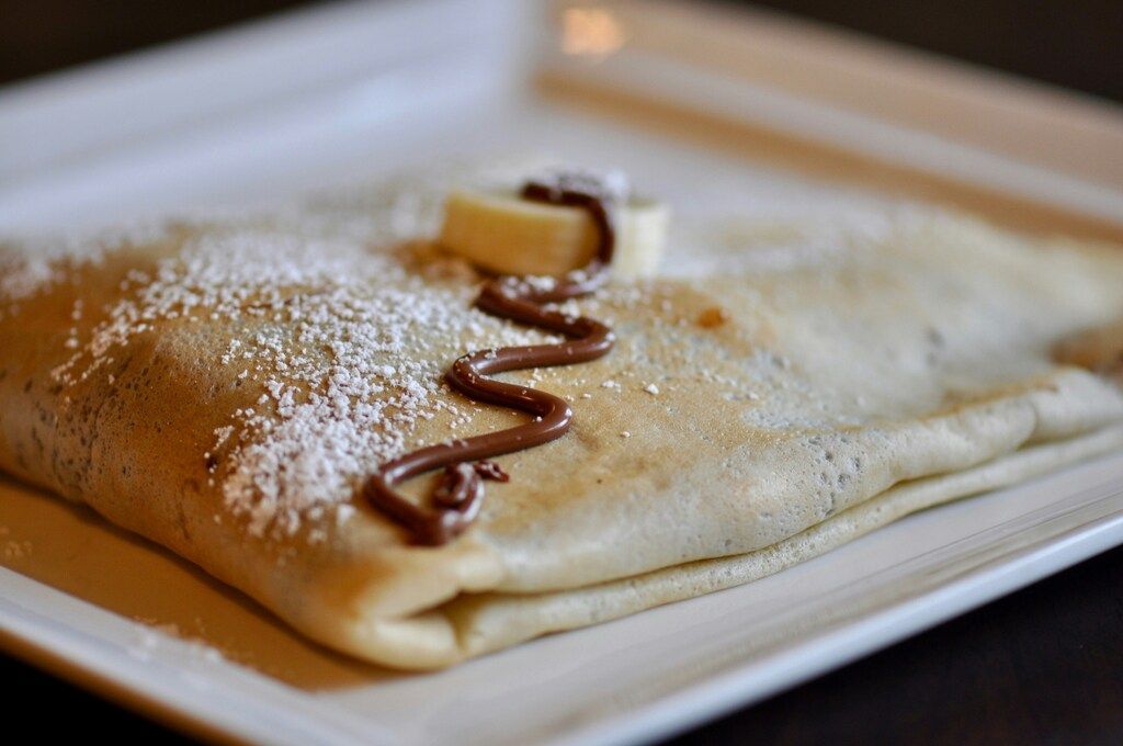 Französischer Crêpe mit Puderzucker, Banane und Schokoladensoße.