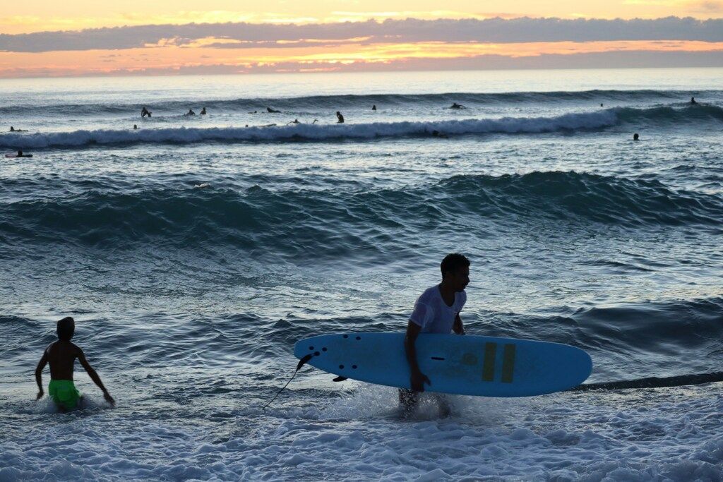 Zwei Surfer gehen bei Sonnenuntergang ins Wasser.