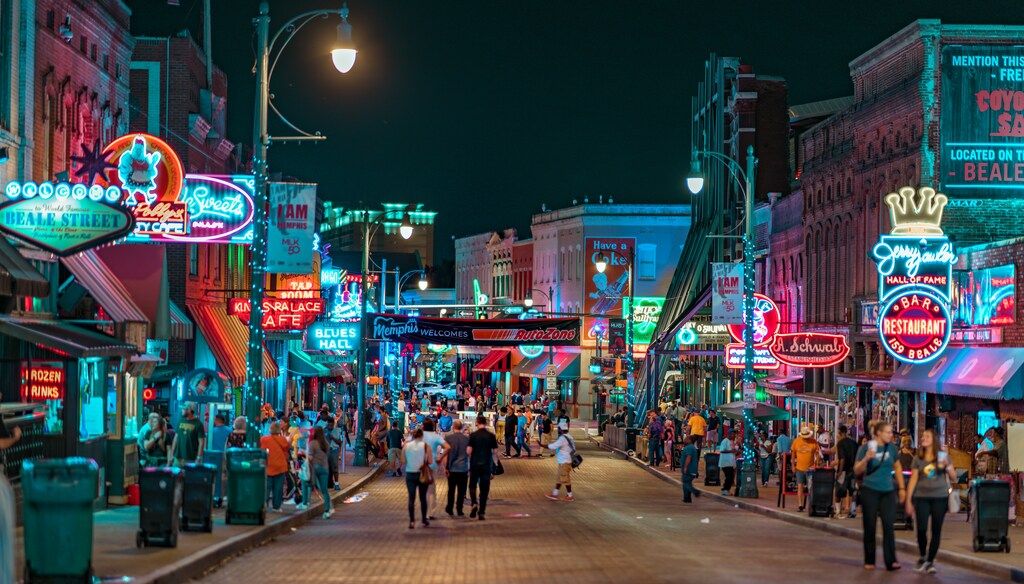 Belebte Beale Street in Memphis bei Nacht mit bunten Neonlichtern und Menschenmenge