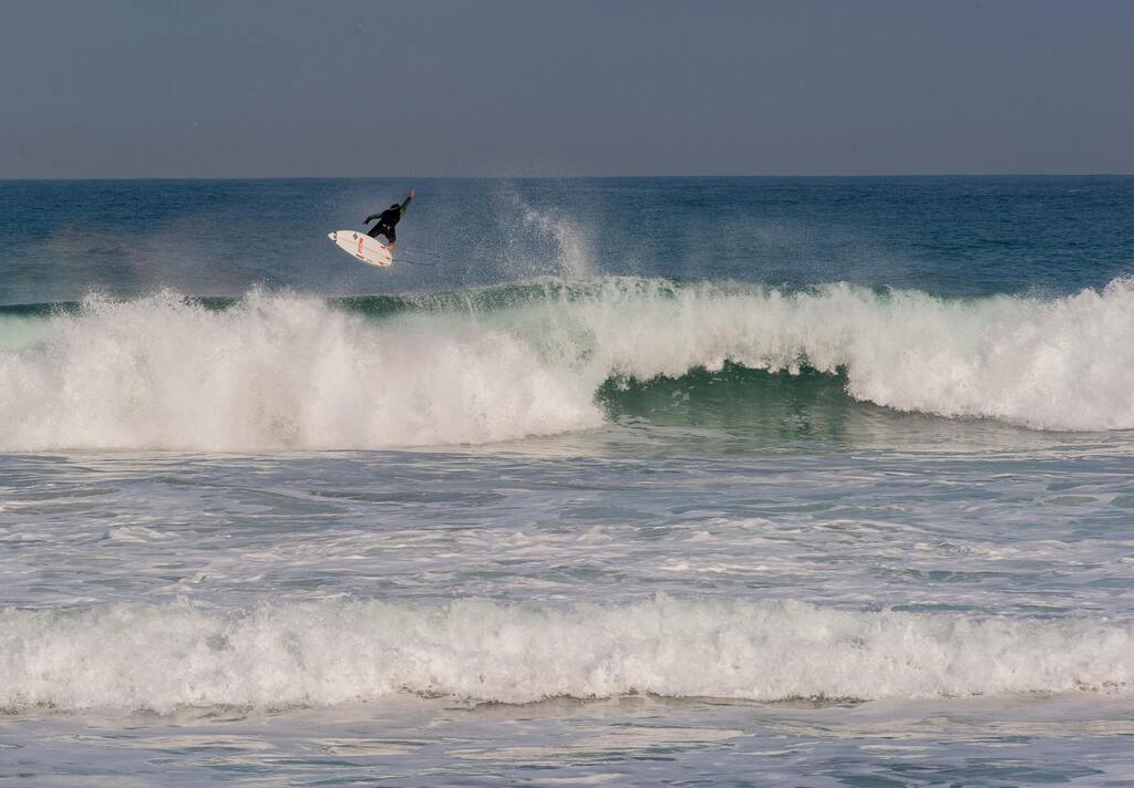 Surfer in der Luft über einer Welle.
