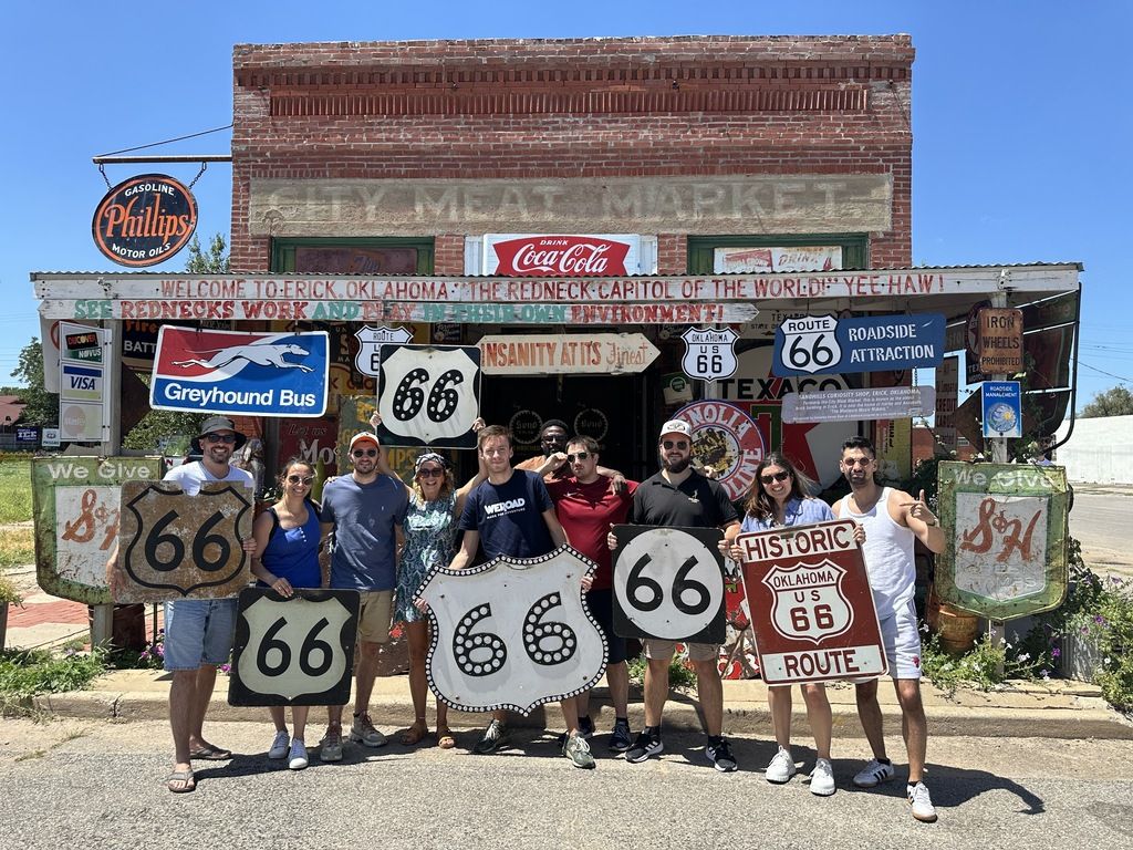 Reisegruppe posiert mit Route-66-Schildern vor einem Vintage-Gebäude in Oklahoma