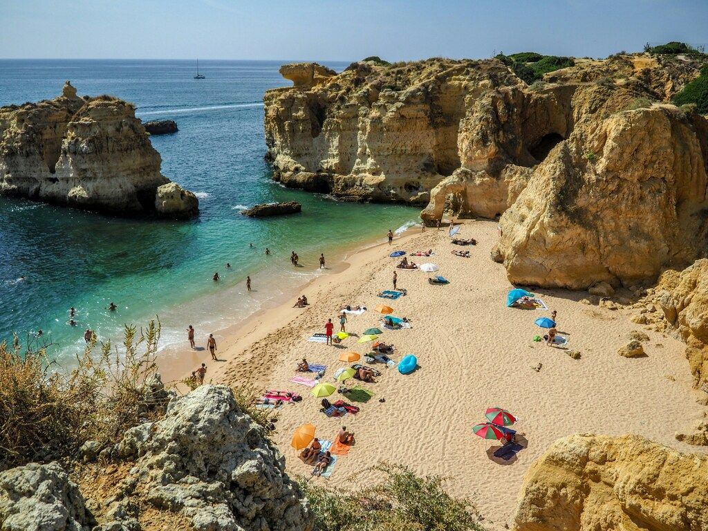 Kleine Badebucht mit goldfarbenem Sand und Felsformationen an der Algarve in Portugal.