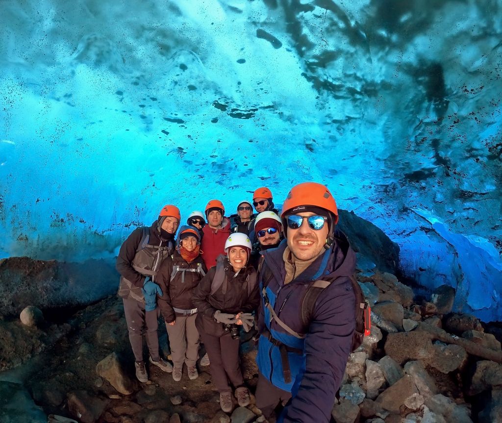 WeRoad-Gruppe mit Helmen in einer leuchtend blauen Eishöhle – ein unvergessliches Abenteuer