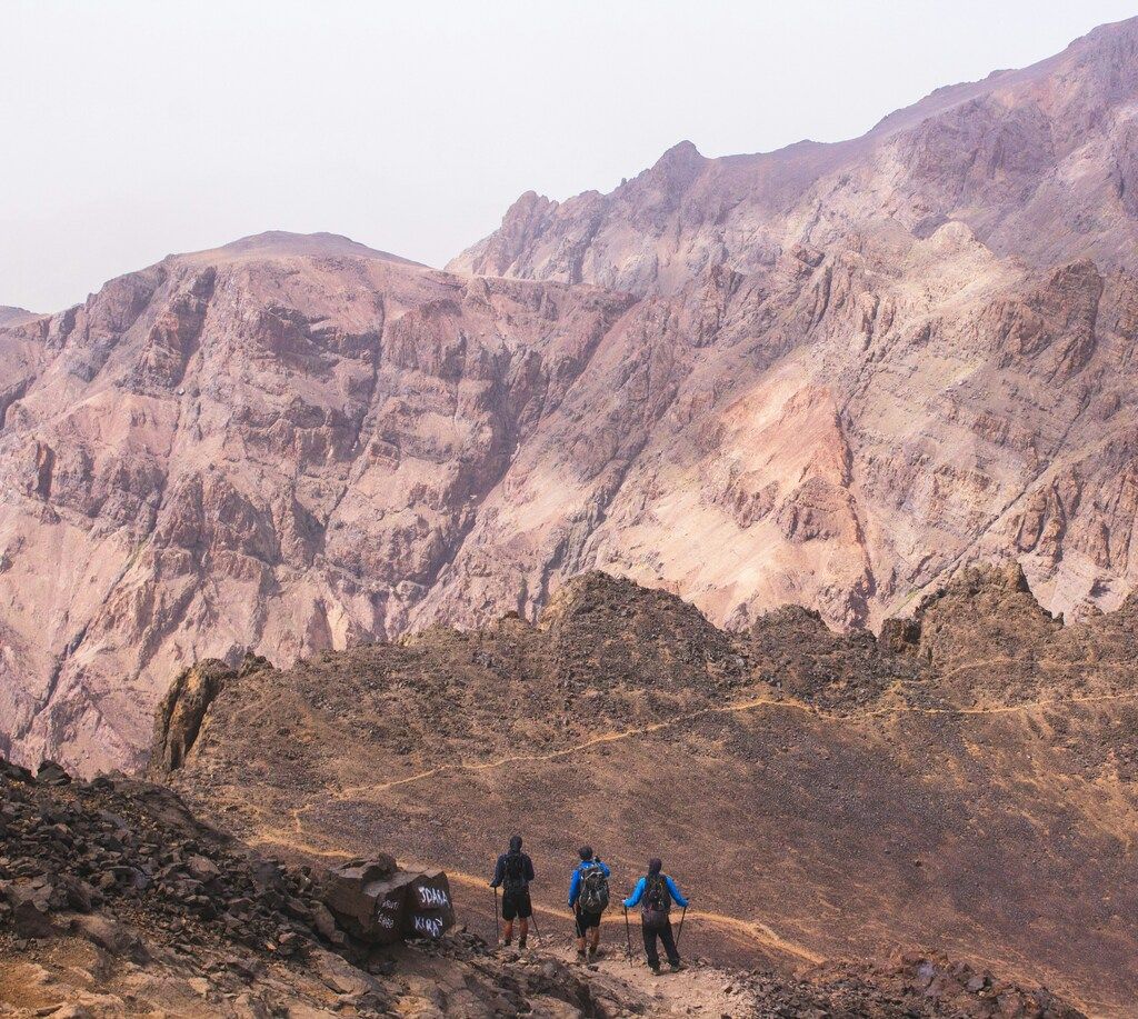 Drei Wanderer auf einer kargen Berglandschaft mit beeindruckenden Felsformationen