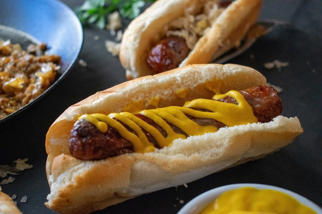 Klassischer Hot Dog mit Bratwurst und Senf im weichen Brötchen