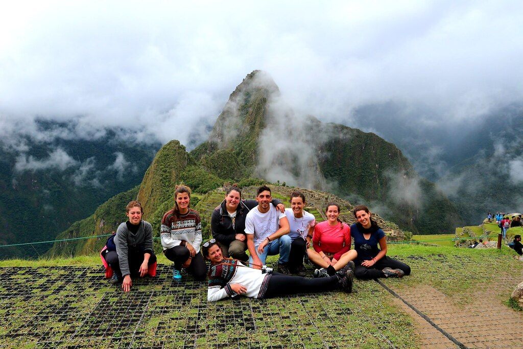 Gruppe von WeRoad-Reisenden posiert vor dem ikonischen Berggipfel von Machu Picchu in Peru.