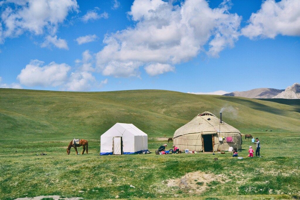 Traditionelle Jurten und Pferde in der weiten kirgisischen Steppe unter einem strahlend blauen Himmel