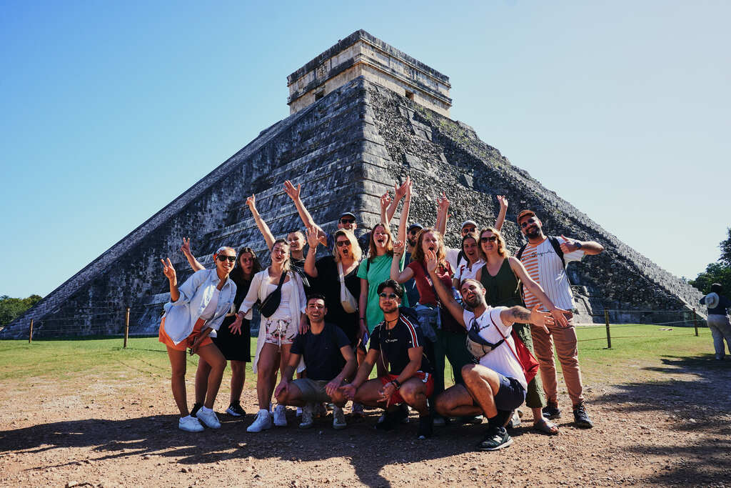 WeRoad-Reisegruppe posiert fröhlich vor der Pyramide von Chichén Itzá