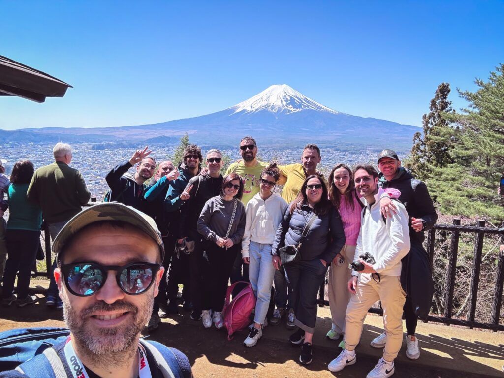 Fröhliche WeRoad-Reisegruppe posiert vor dem majestätischen Fuji in Japan bei strahlendem Sonnenschein
