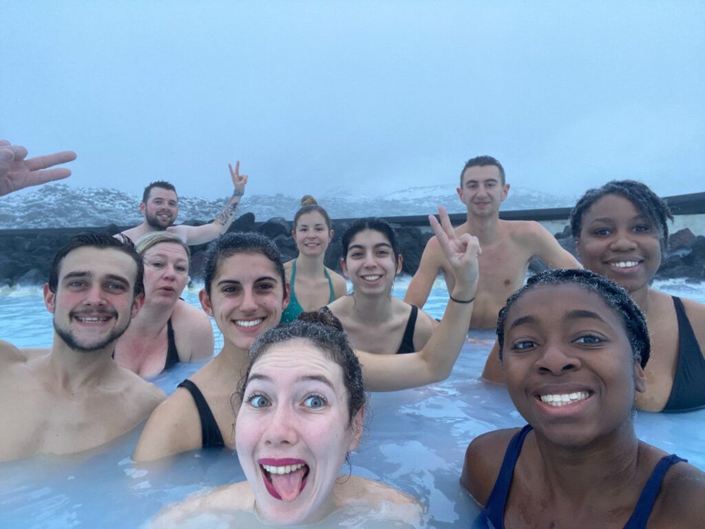 WeRoad-Reisegruppe genießt gemeinsam die berühmte Blaue Lagune in Island, umgeben von dampfendem Thermalwasser und verschneiter Landschaft.