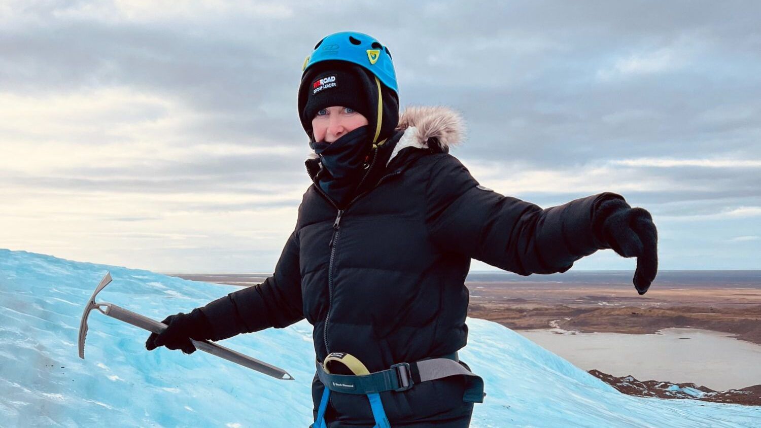 Reisende mit Eispickel und Steigeisen auf blauem Gletschereis in Island.