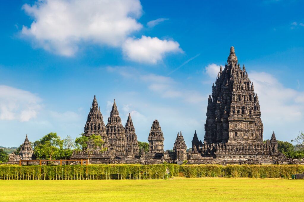 Der majestätische Hindu-Tempelkomplex Prambanan auf Java bei klarem Himmel und grünem Rasen.