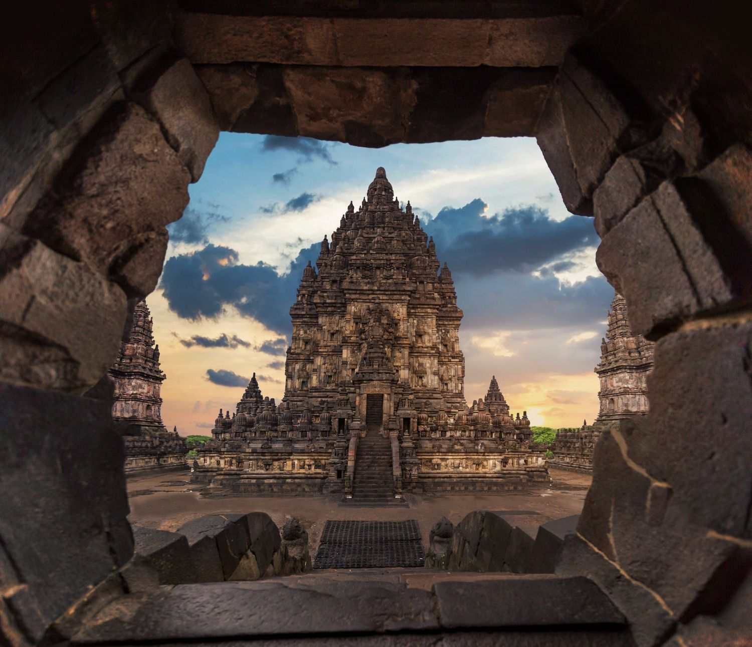 Detailaufnahme des Prambanan Tempels, durch einen steinernen Durchgang bei Sonnenuntergang gerahmt.