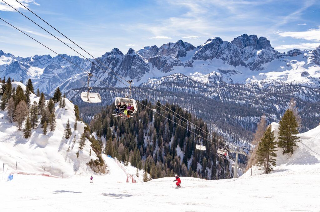 Sonnige Skipiste in den Dolomiten mit Seilbahn und schneebedeckten Bergen.