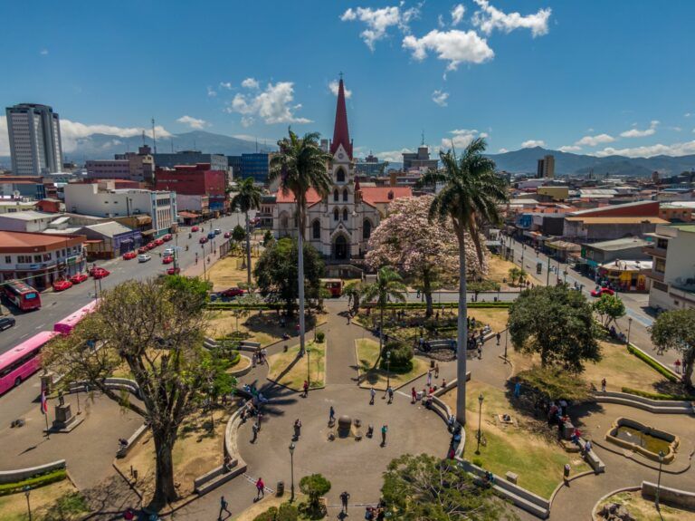Luftaufnahme des Parque Morazán in San José, Costa Rica, mit der markanten Metallkirche (Iglesia de la Merced) im Hintergrund unter einem blauen Himmel.