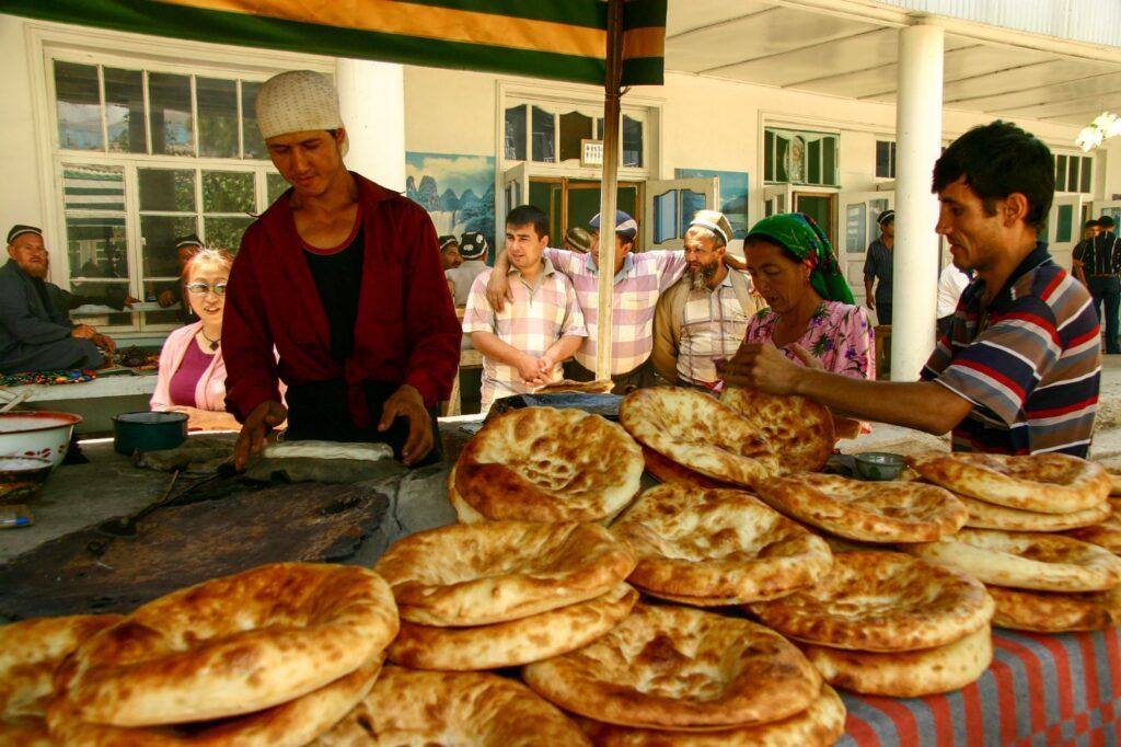 Verkäufer an einem Marktstand in Usbekistan präsentieren frisch gebackenes traditionelles Fladenbrot (Non).