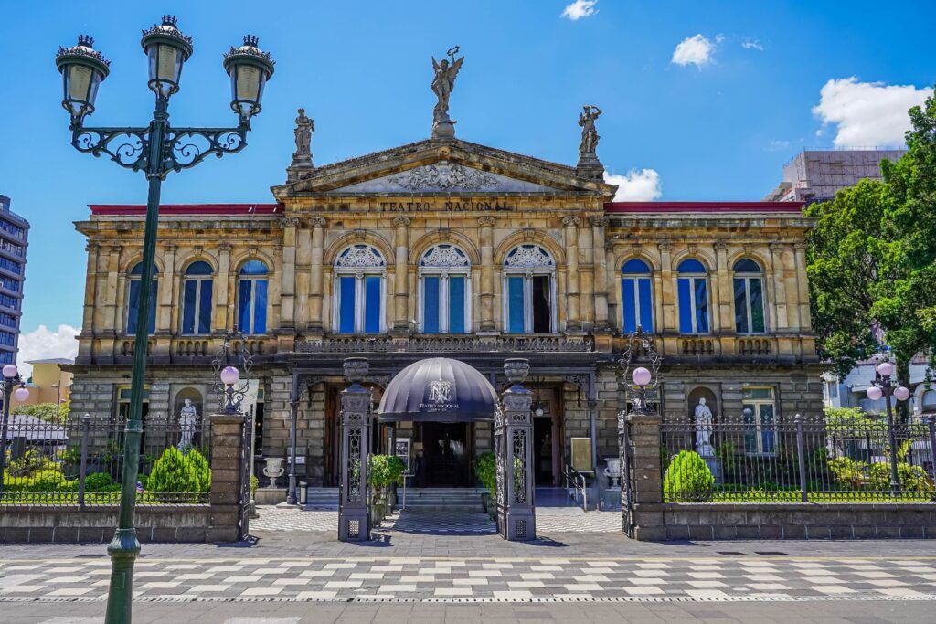 Die imposante Steinfassade des Nationaltheaters von Costa Rica in San José, verziert mit klassischen Statuen unter einem strahlend blauen Himmel.