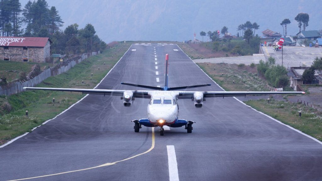 Ein kleines Propellerflugzeug auf der Start- und Landebahn eines Flughafens in den Bergen von Nepal.
