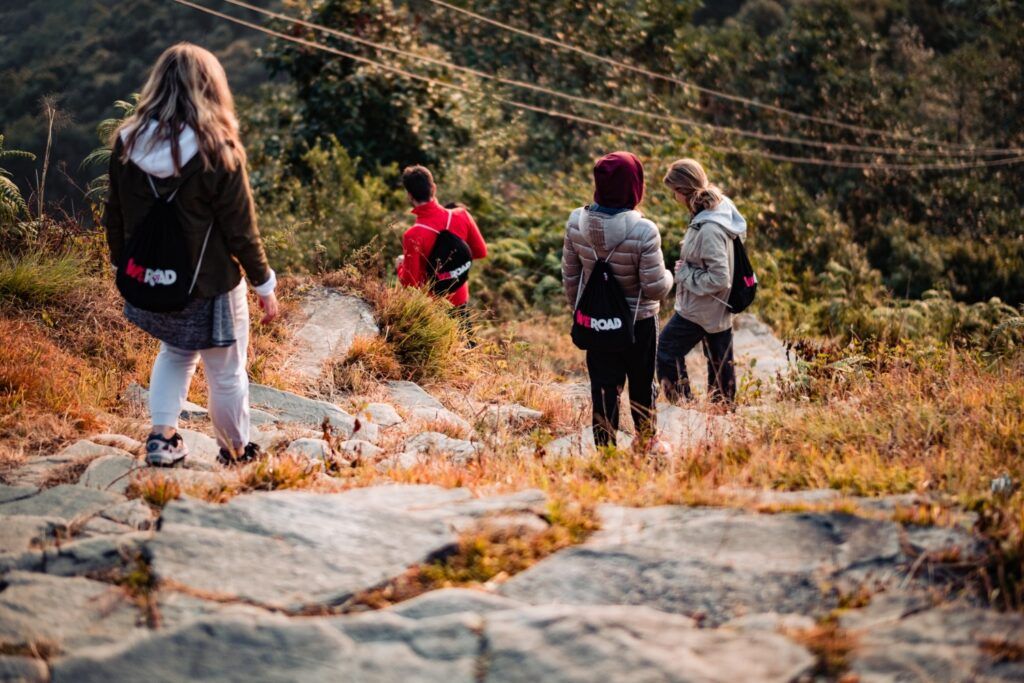 Eine Gruppe von WeRoad-Wanderern mit Rucksäcken auf einem felsigen Pfad in den Bergen Nepals.