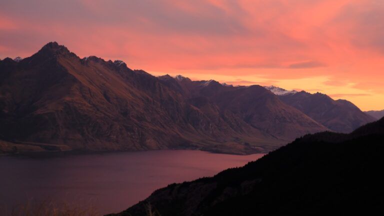 Spektakulärer Sonnenuntergang über neuseeländischen Bergen und einem See in intensiven Rosa- und Orangetönen.