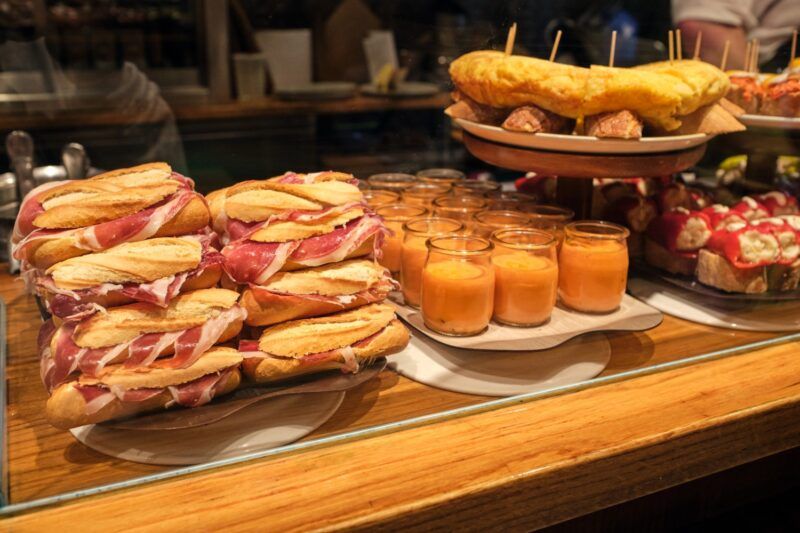Spanischen Tapas, wie Schinken-Sandwiches und Tortilla-Stücke, auf einem Tresen.
