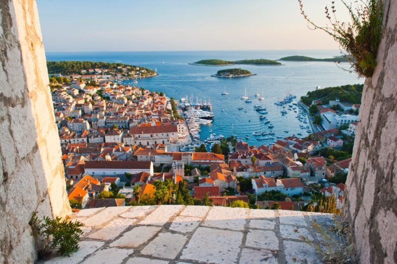 Panoramablick auf die Stadt Hvar bei Sonnenuntergang mit ihrem Hafen voller Boote und den umliegenden Inseln in der Adria.