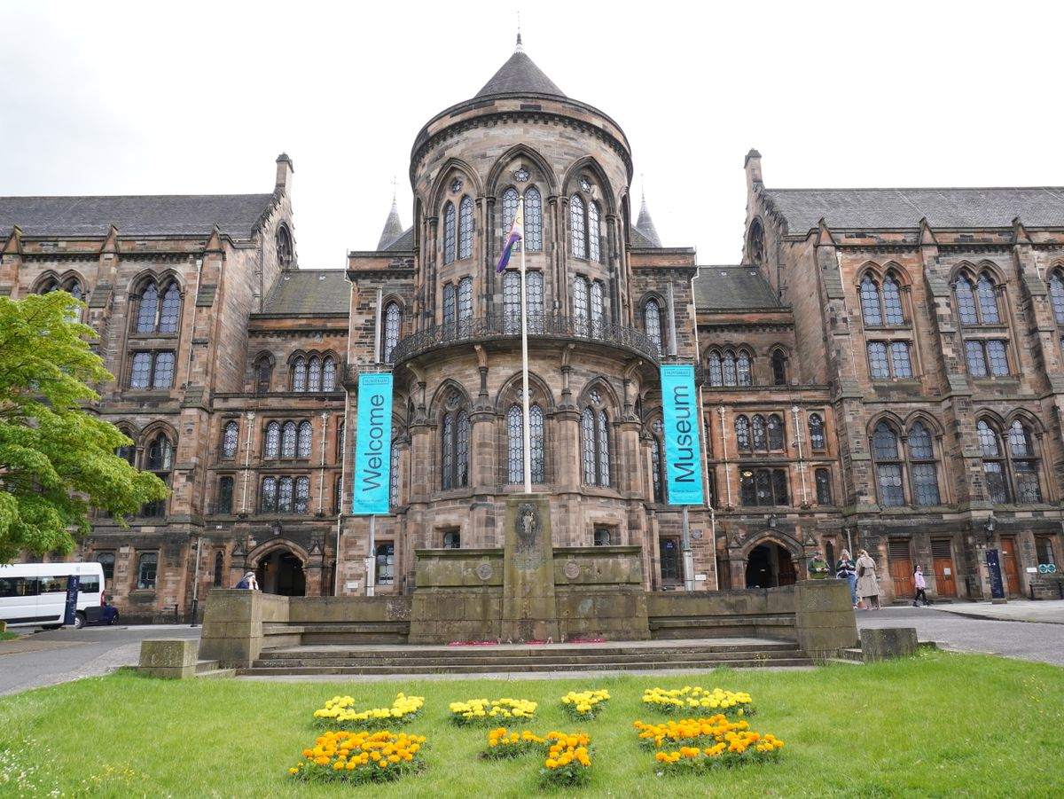 Historisches Hauptgebäude der University of Glasgow mit Museumsbannern und Rasenfläche