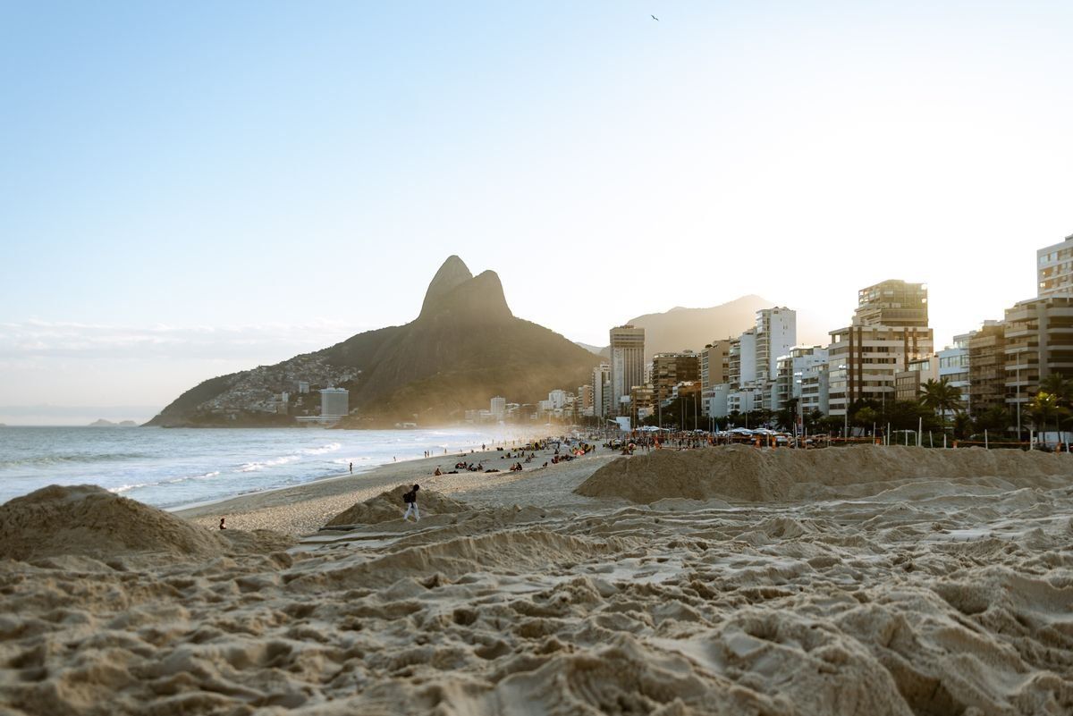 Ipanema-Strand mit sandigem Vordergrund, Stadtgebäuden und markantem Berg im Abendlicht