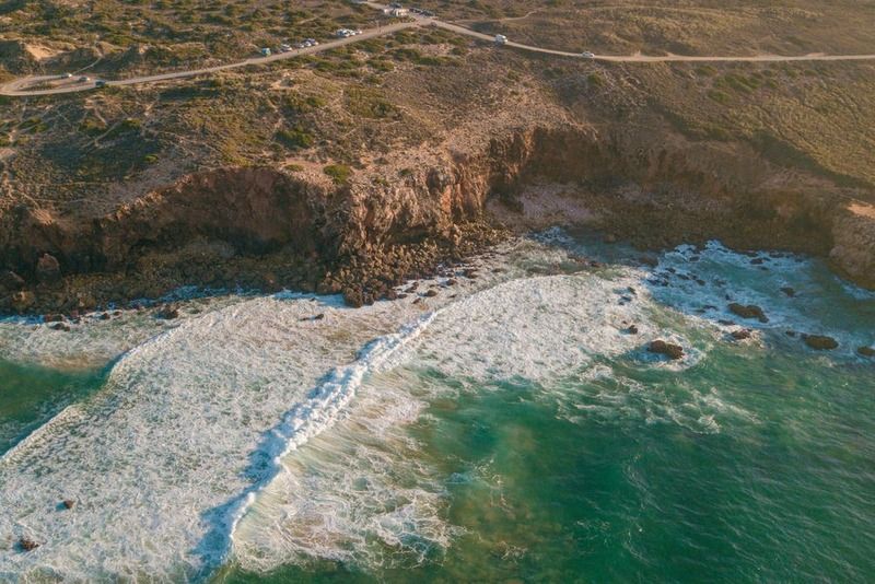 Luftaufnahme der Klippen und brechenden Wellen am Strand von Odeceixe an der Westküste Portugals