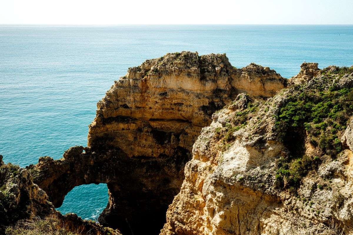 Goldene Felsklippen mit natürlichem Felsbogen über ruhigem blauem Meer