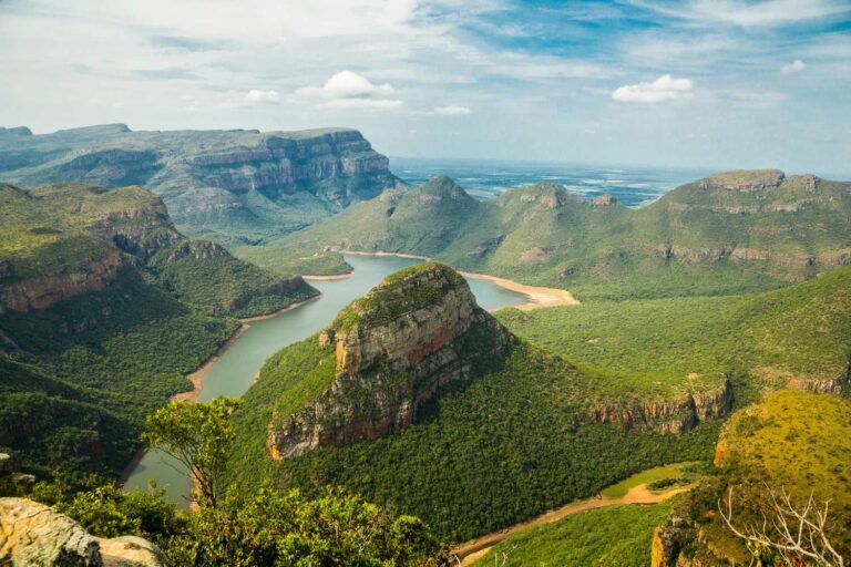 Luftaufnahme einer dramatischen Schlucht mit einem gewundenen Fluss durch grüne Berge in Südafrika