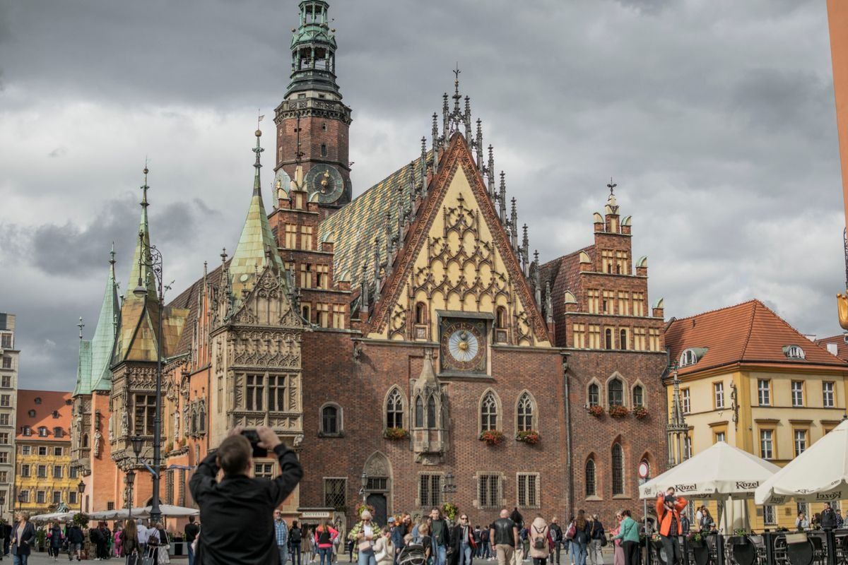 Rathaus am Marktplatz in Breslau mit Passanten unter dunklen Wolken
